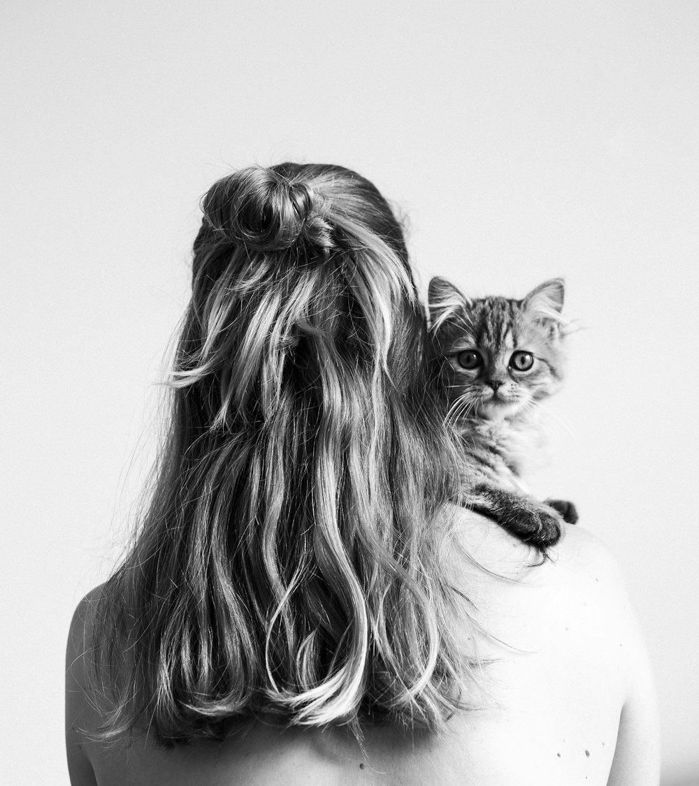 Foto in scala di grigi di donna che trasporta un gattino