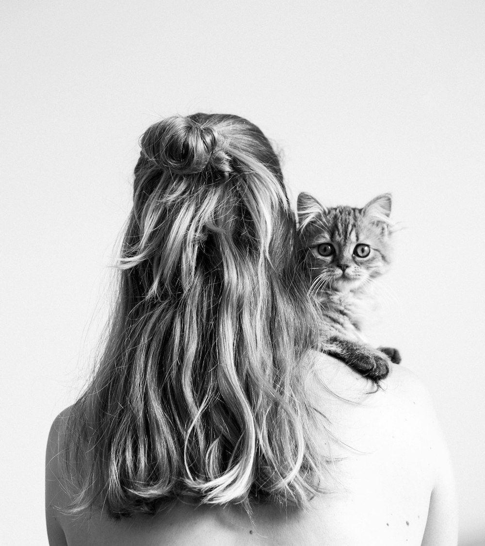 grayscale photo of woman carrying a kitten