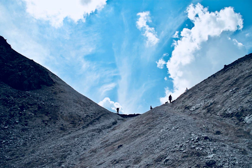 Adventurers trekking through rocky landscapes under a clear blue sky.