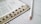 A close-up view of an open book with visible text and black tabs along the side. A white pencil lies next to the book on a light-colored wooden surface.