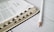A close-up view of an open book with visible text and black tabs along the side. A white pencil lies next to the book on a light-colored wooden surface.