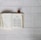 An open book with text in both Chinese and English lies on a white wooden surface. A small pine cone is placed above the book.