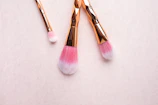 Soft pastel-hued makeup brushes resting on a gold-trimmed marble vanity.