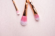 Elegant makeup brushes resting on a blush pink silk cloth with soft natural light.