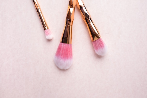 A minimalist makeup brush set displayed neatly on a soft pink fabric.