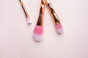 Soft pastel-toned makeup brushes arranged elegantly on a light wooden surface.