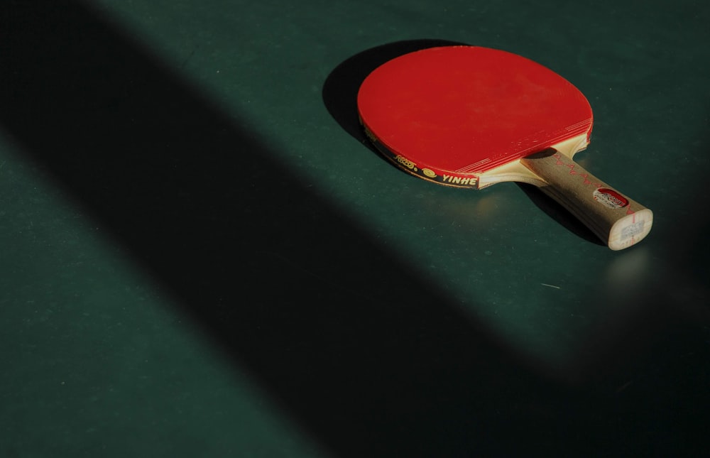 Mesa de ping pong roja y marrón sobre panel verde