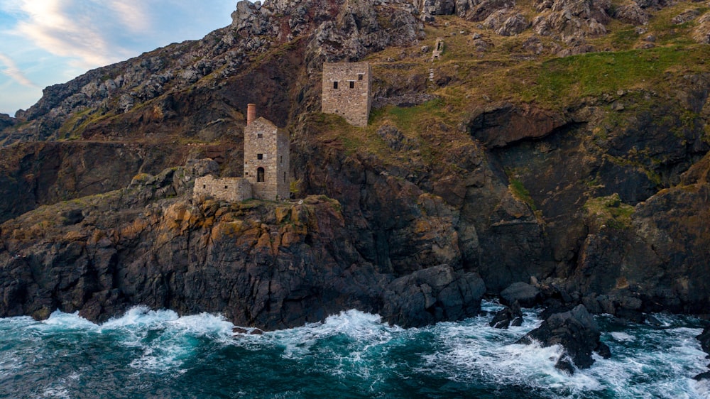 gray brick tower at cliff near ocean at daytime