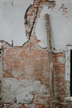 brown wood branch leaning on gray and brown concrete wall