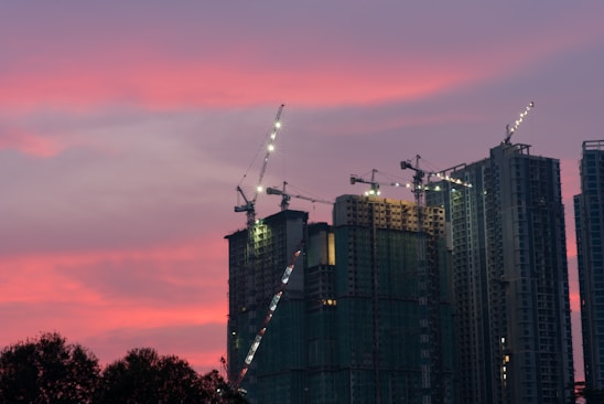 A bustling city skyline under construction at sunset, symbolizing growth and economic activity.