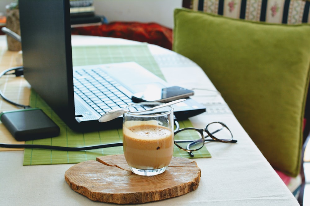 half full half empty drink in clear drinking glass on table beside laptop