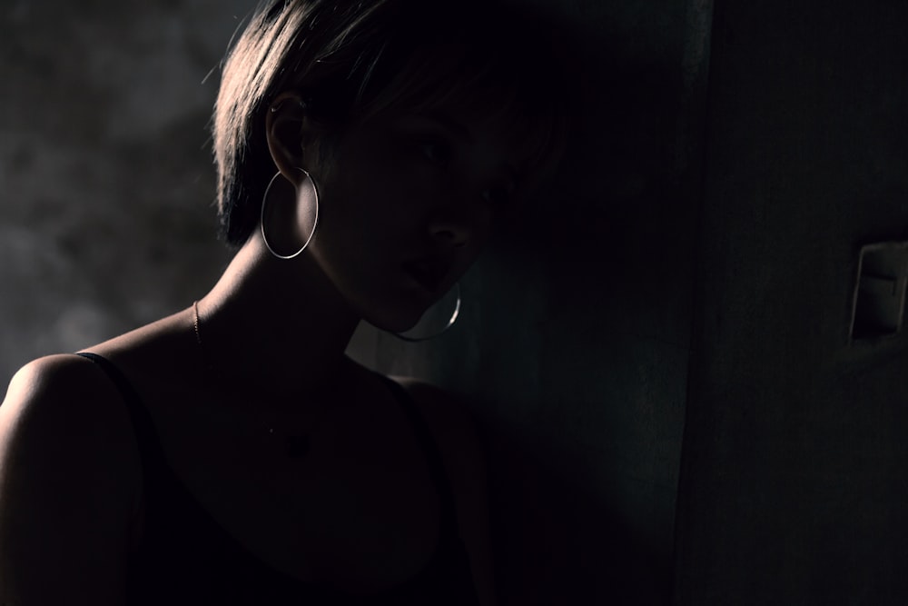 Une femme appuyée contre un mur dans une pièce sombre