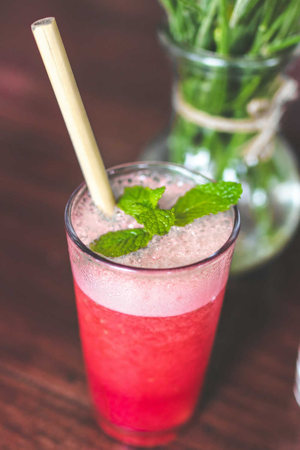 shallow focus photography of clear drinking glass with pink liquid on brown wooden surface