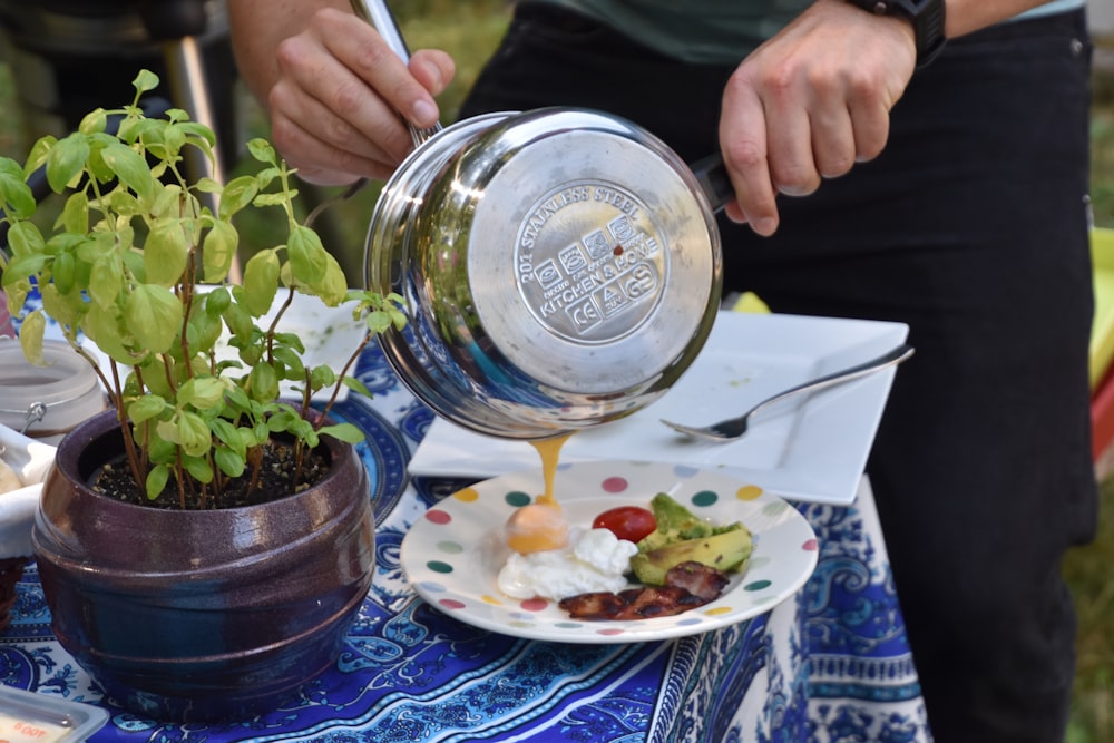 person holding pot pouring sauce on plate