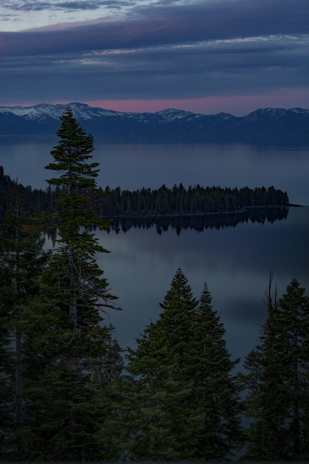 Silhouettenfotografie von Wald und Berg in der Nähe eines Gewässers