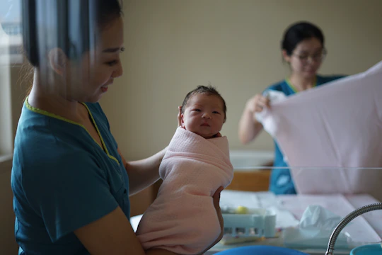 A caring nurse gently cradling a newborn wrapped in a soft blanket.