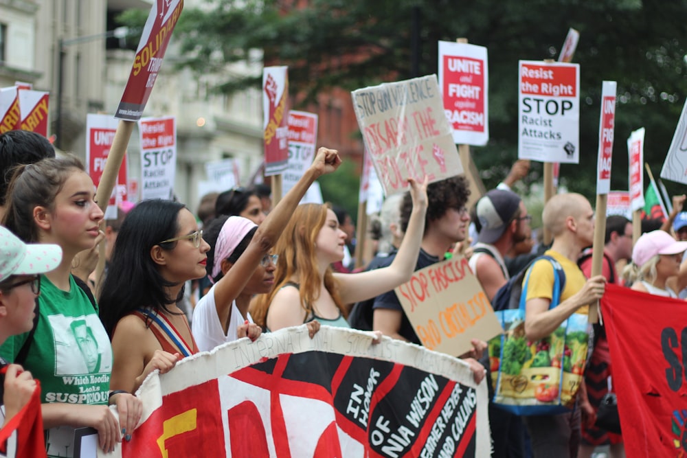 group of people holding signage and raising their hands during daytime