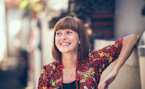 woman in floral-themed cardigan leaning on fence in bokeh photography