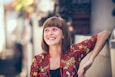 woman in floral-themed cardigan leaning on fence in bokeh photography