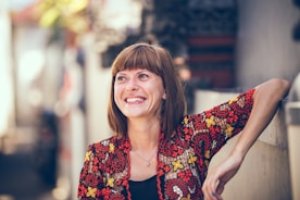 woman in floral-themed cardigan leaning on fence in bokeh photography