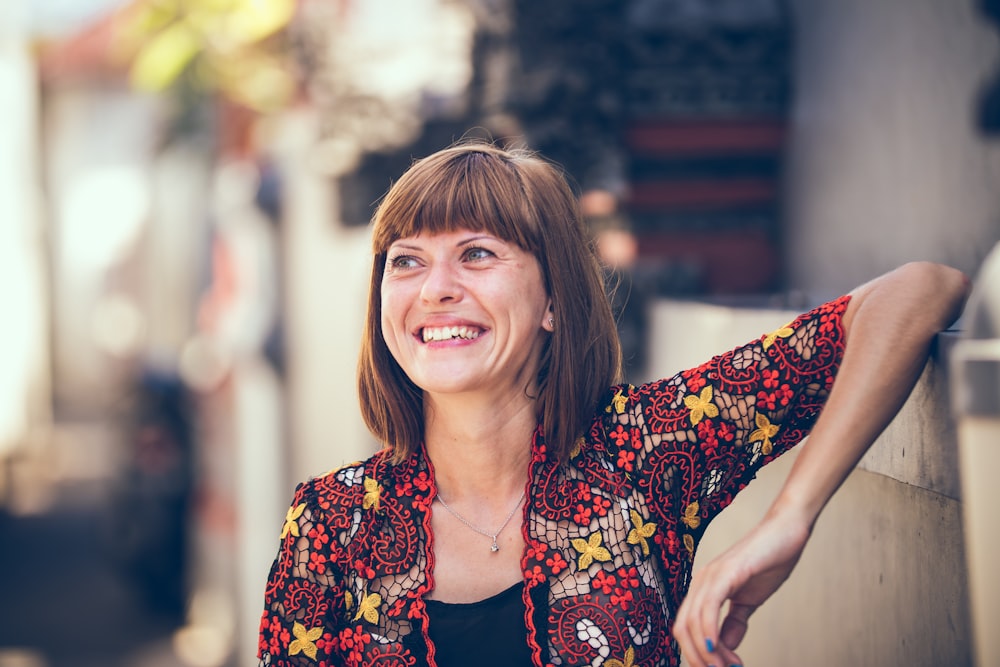 Frau in floraler Strickjacke, die sich in der Bokeh-Fotografie an einen Zaun lehnt