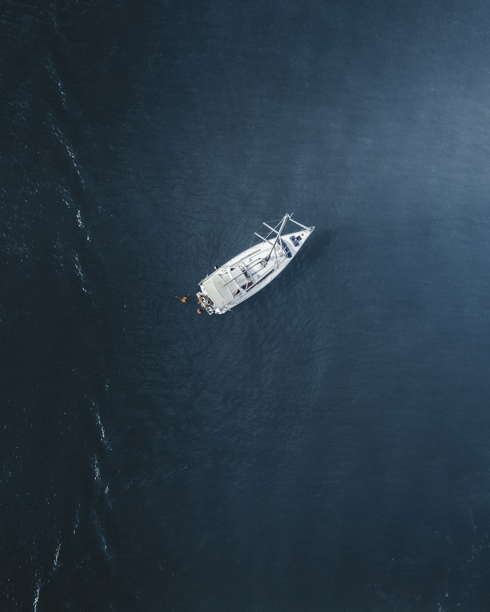 Luftaufnahme einer weißen Yacht, die tagsüber auf dem Wasser segelt