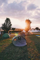 A tent meeting at dusk with a crowd listening intently as the gospel is shared, golden light glowing warmly over the scene.