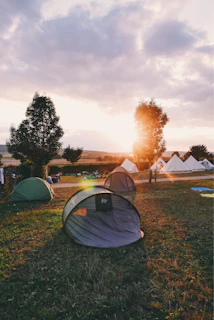 A tent meeting at dusk with a crowd listening intently as the gospel is shared, golden light glowing warmly over the scene.