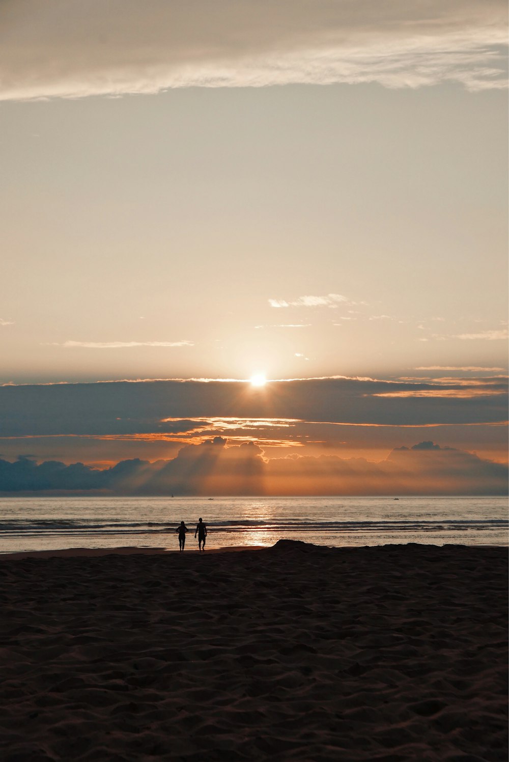 silhouette of man and woman walking on sea shore during sun set