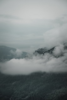 A peaceful mountain view with clouds drifting above the peaks.