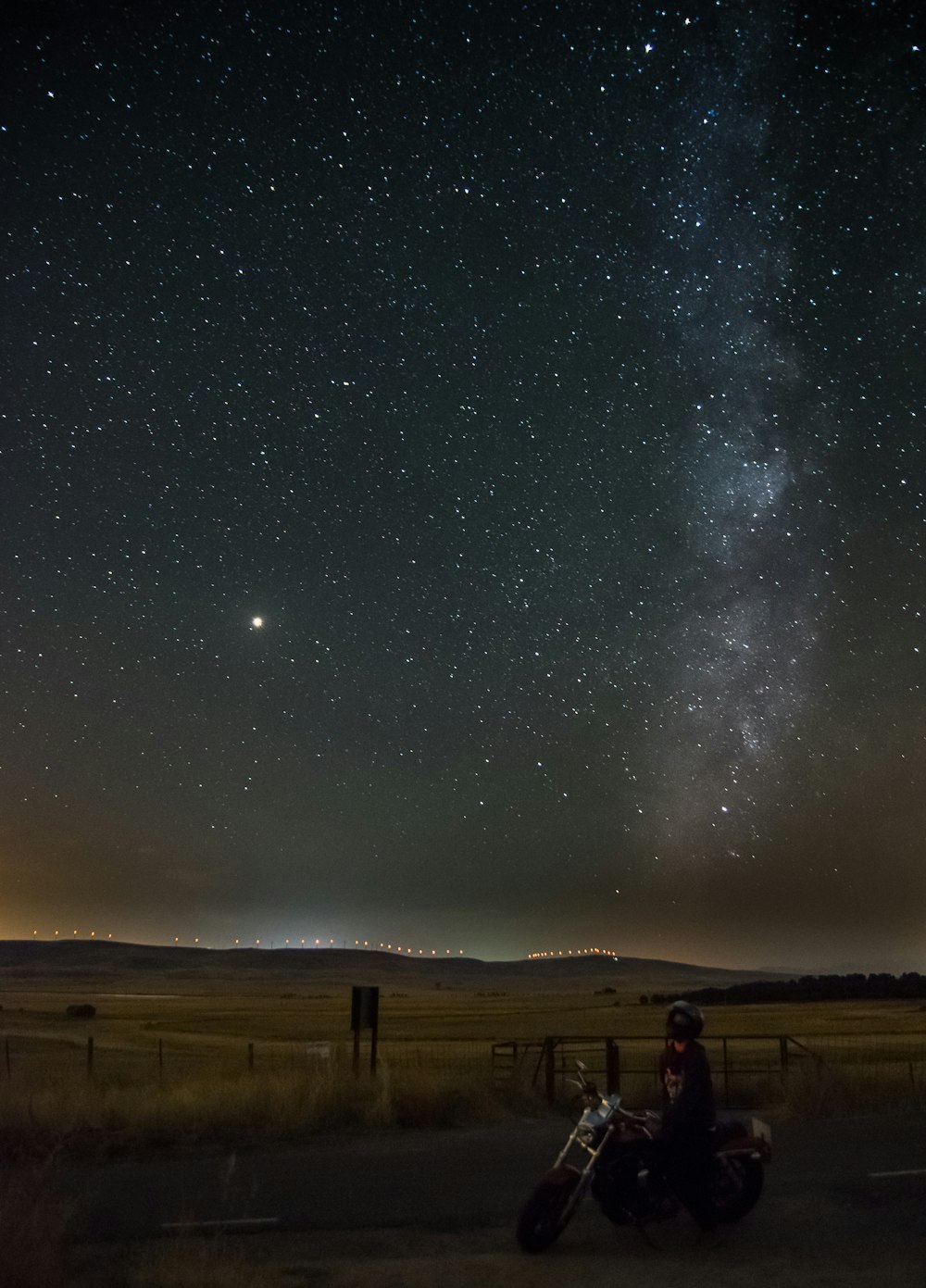 person rides on motorcycle under starry sky