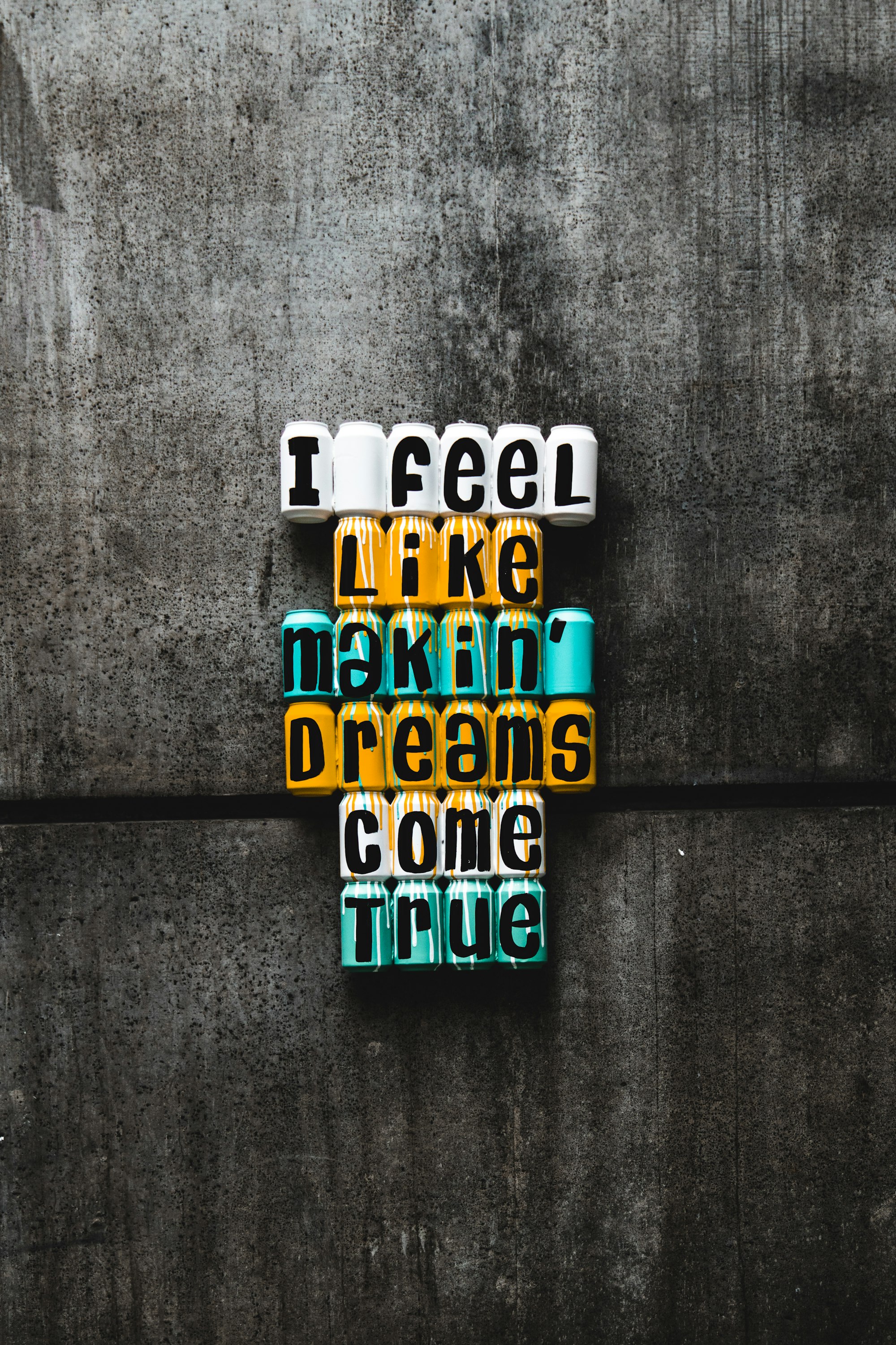 Colourful soda cans painted with text that says "I feel like makin' dreams come true"