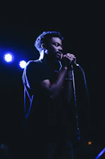 Close-up of hands holding a microphone with soft lighting and a dark background.