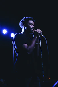 Close-up of hands holding a microphone with soft lighting and a dark background.