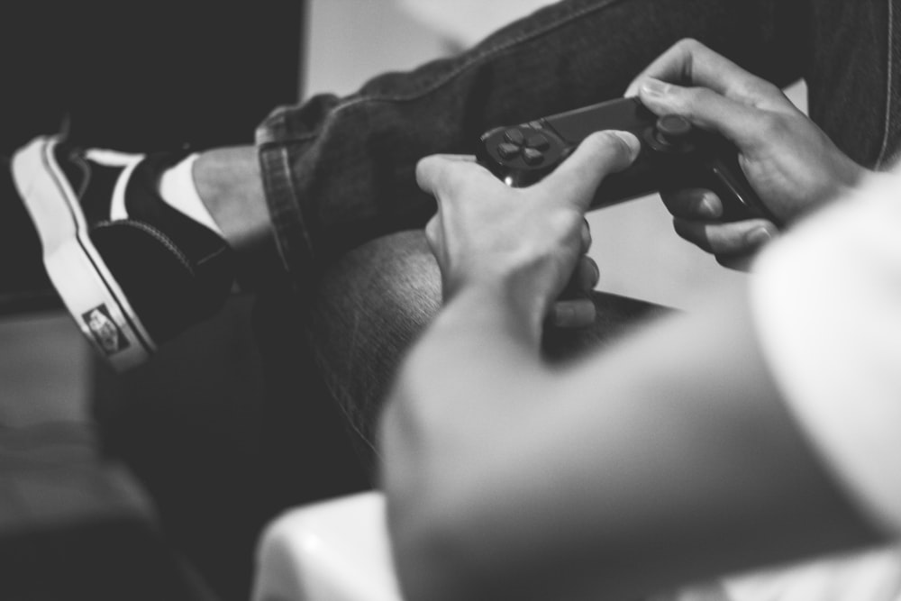 grayscale photo of man playing on game controller