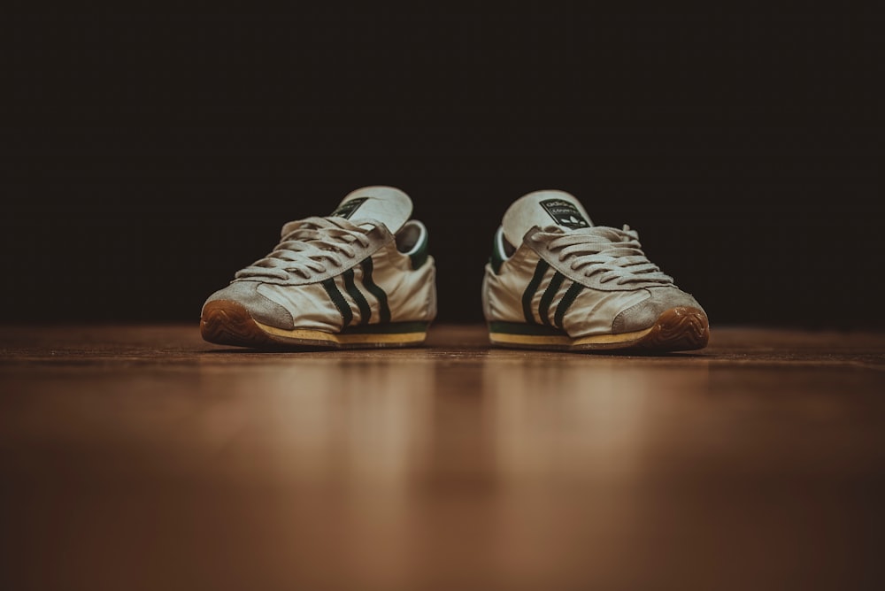 pair of gray adidas low-top sneakers on brown wood