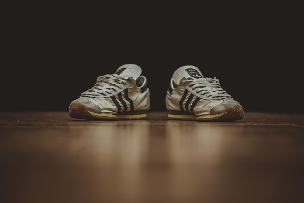 pair of gray adidas low-top sneakers on brown wood