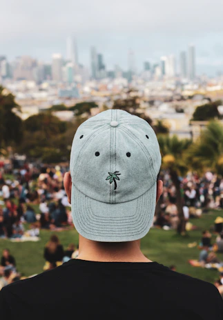 Casual shot of a zero2it cap worn by a person outdoors with a city skyline in the background.