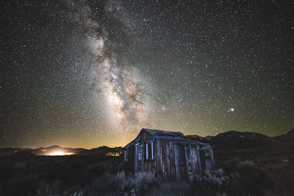 夜の空の星空の下の茶色と灰色の木造家屋