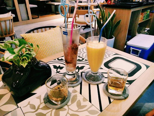 A cozy café table with dinosaur-themed cups and plates filled with colorful drinks and treats.