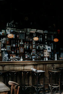 Warm, dimly lit interior of Oak & Ember showcasing polished wooden bar and shelves lined with whiskey bottles and wine glasses.