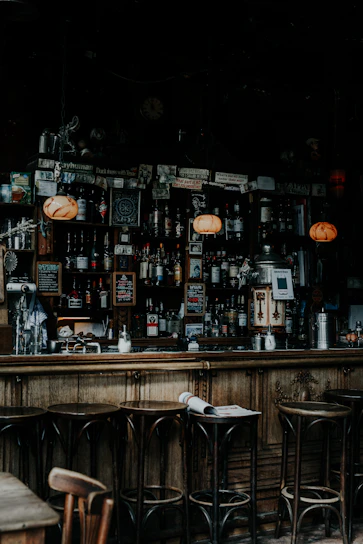 Warm, dimly lit interior of Oak & Ember showcasing polished wooden bar and shelves lined with whiskey bottles and wine glasses.