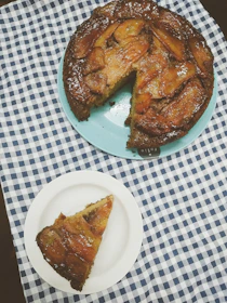 Top view of several slices of banana sponge cake with creamy cheese filling on a wooden board with fresh bananas.
