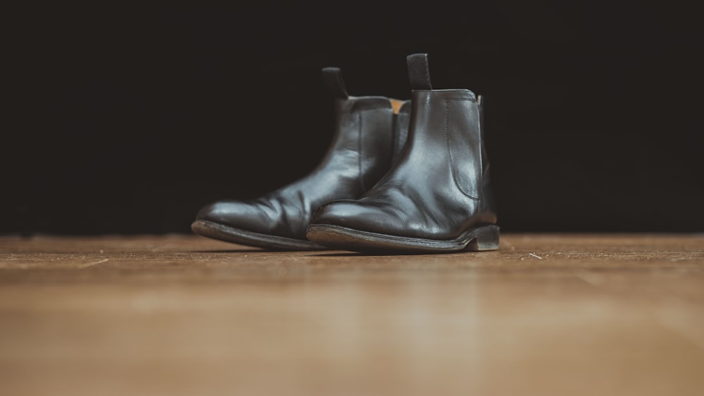 pair of black leather boots on brown surface
