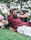 man in maroon dress shirt lying on green grass field