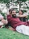 man in maroon dress shirt lying on green grass field