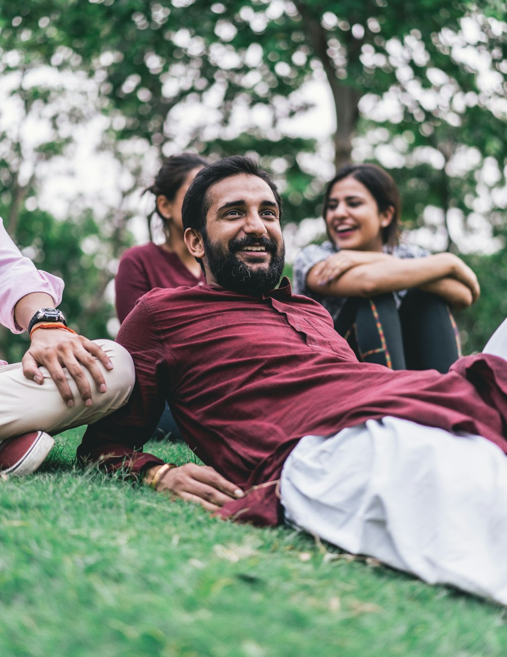 man in maroon dress shirt lying on green grass field