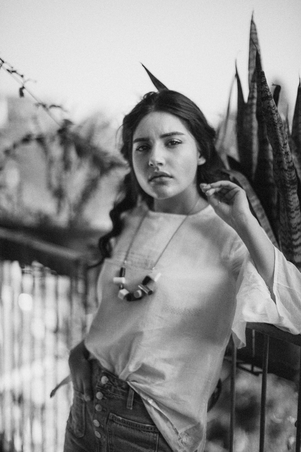 grayscale photo of woman leaning on black rail