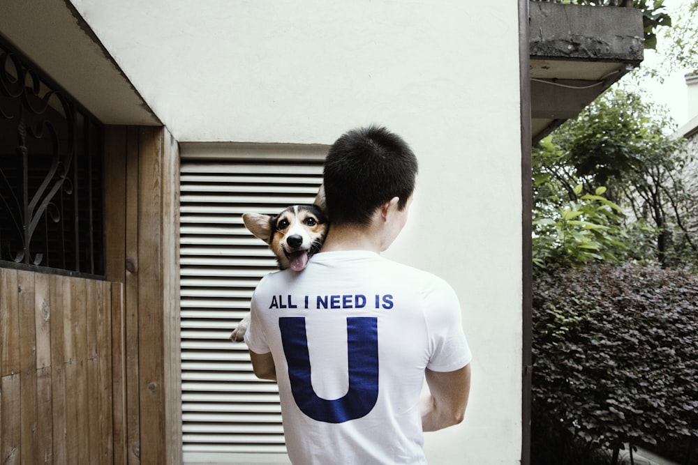 man carrying adult Pembroke Welsh corgi