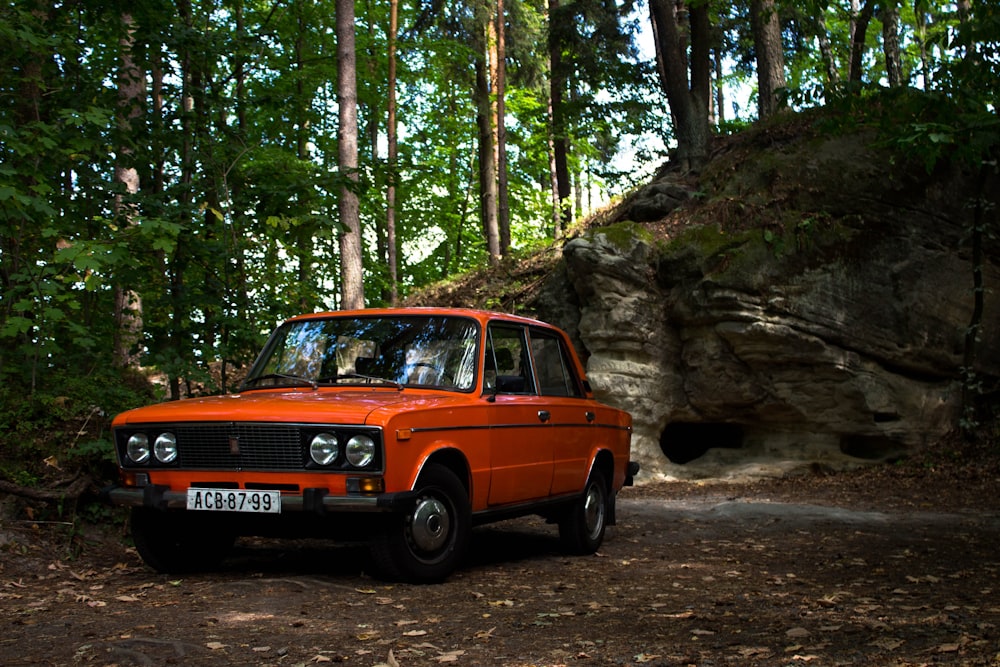 orange sedan in forest field during daytime